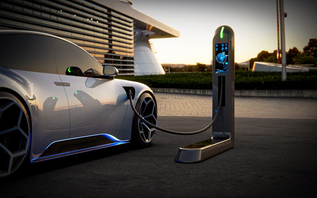 Electric sports car being charged by an EV charger at sunset