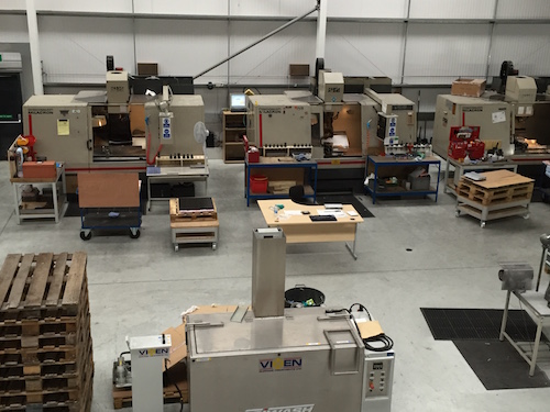 A modern and clean CNC shop, showing 4 CNC machines with pallets next to one of the machines