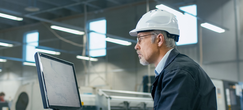 Senior engineer in glasses and a hard hat is working on a desktop computer in a factory, looking for components. GD Rectifiers terms & conditions.