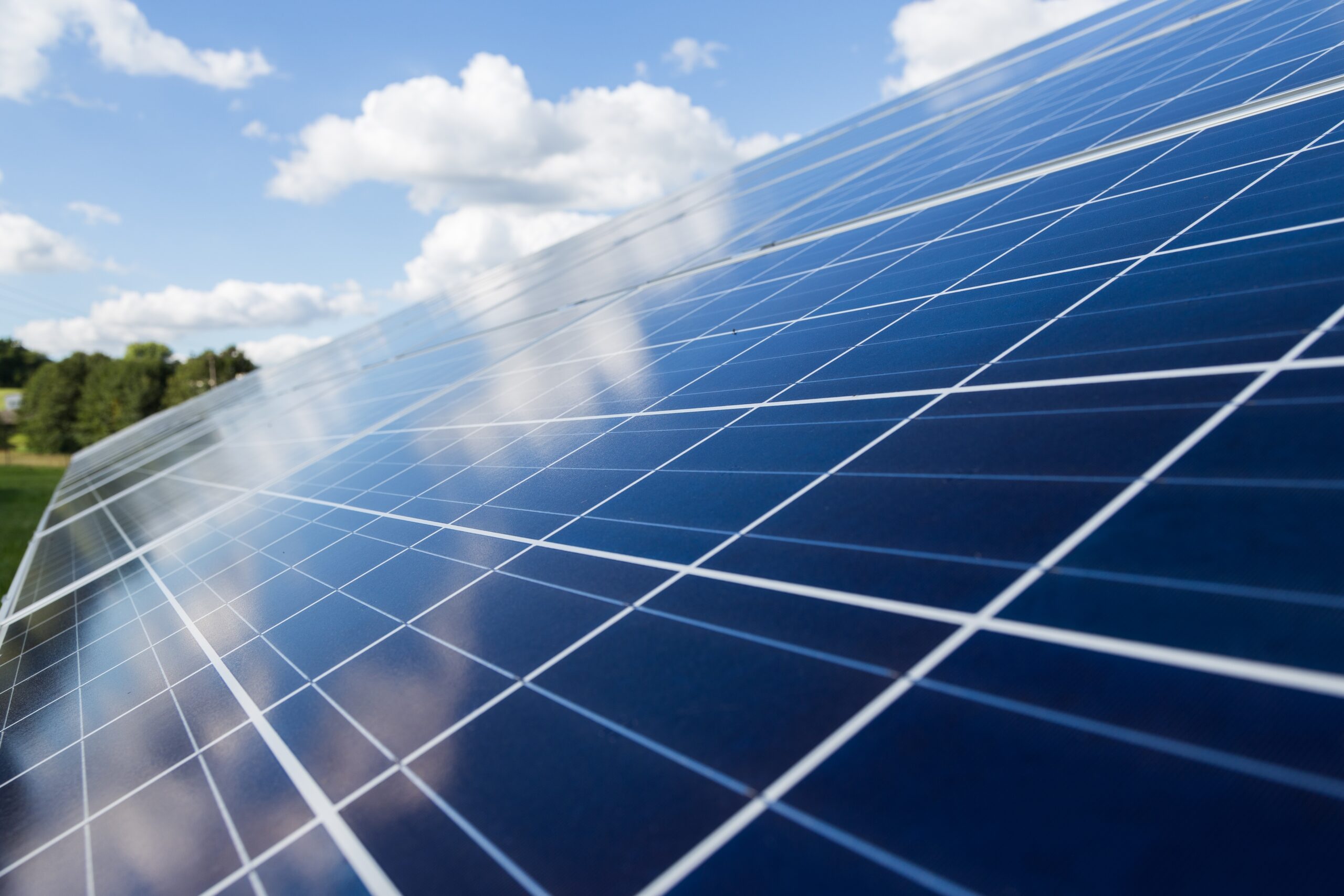 Solar protection image, sun shining on solar panels, bright blue sky and white clouds.